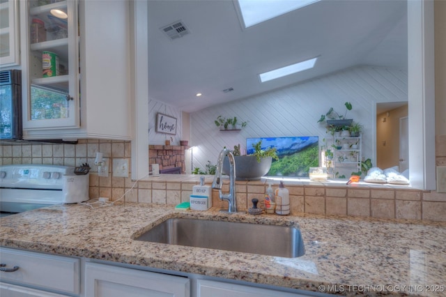 3249 S 138th E Ave, Tulsa, OK 74134 - kitchen featuring white cabinets, a sink, tasteful backsplash, vaulted ceiling with skylight, and glass insert cabinets
