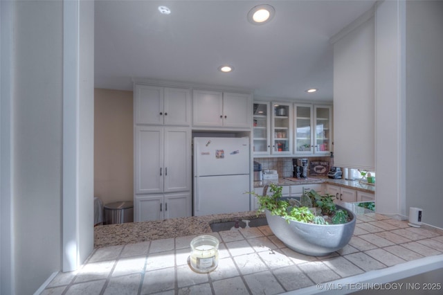 3249 S 138th E Ave, Tulsa, OK 74134 - kitchen featuring freestanding refrigerator, recessed lighting, backsplash, glass insert cabinets, and light countertops