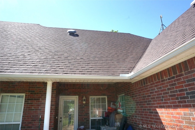 details featuring a shingled roof and brick siding