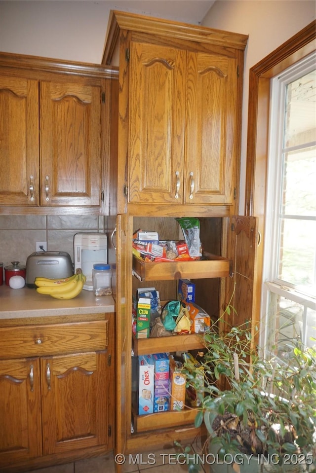 kitchen featuring brown cabinetry, backsplash, and light countertops