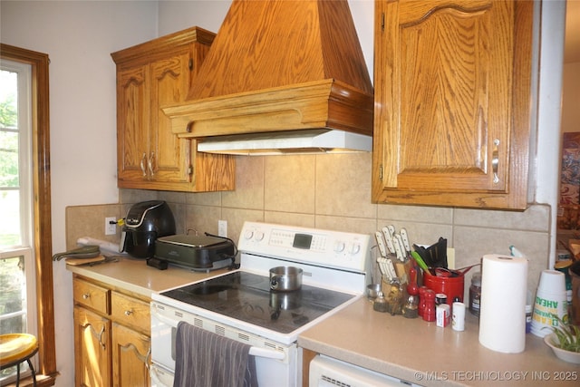 kitchen with tasteful backsplash, white electric stove, light countertops, and custom range hood