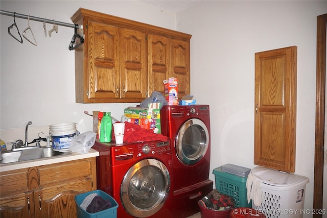 laundry room featuring washing machine and dryer, cabinet space, and a sink