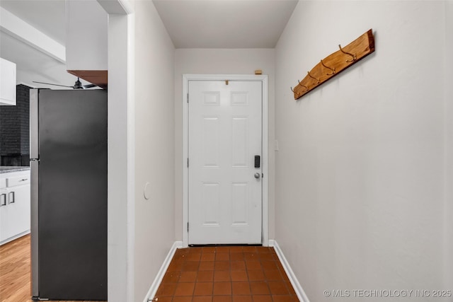 doorway with tile patterned floors and baseboards