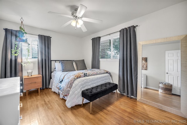 bedroom featuring light wood-style flooring, a ceiling fan, and multiple windows