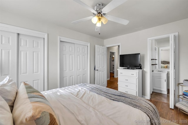 bedroom featuring a ceiling fan, multiple closets, and dark wood-style floors