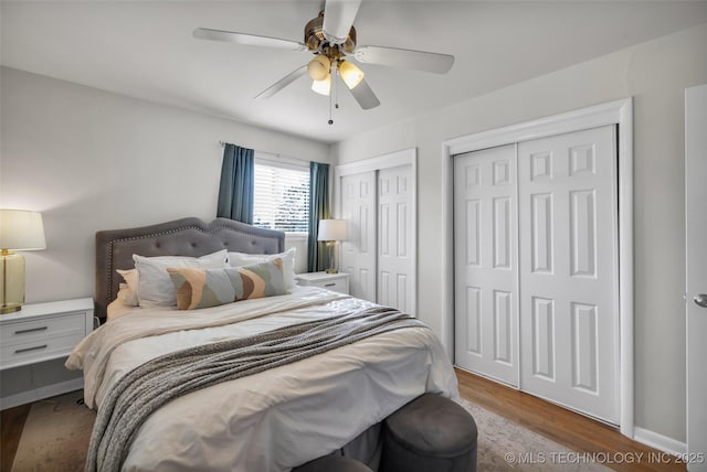 bedroom with ceiling fan, wood finished floors, and multiple closets