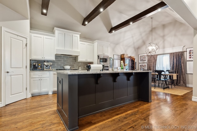 18510 E 46th Pl S, Tulsa, OK 74134 - kitchen featuring stainless steel microwave, a chandelier, high vaulted ceiling, white cabinetry, and a center island with sink