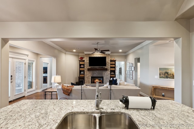 18510 E 46th Pl S, Tulsa, OK 74134 - kitchen featuring a ceiling fan, a fireplace, light stone countertops, wood finished floors, and a sink