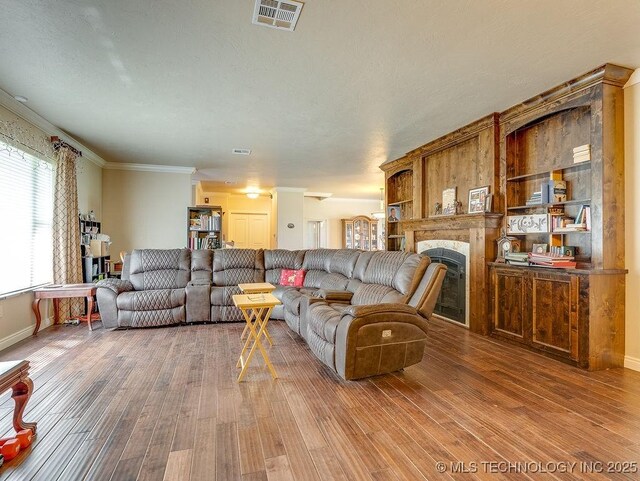21125 State Highway 99 S, Stonewall, OK 74871 - living area with wood finished floors, visible vents, crown molding, baseboards, and a fireplace