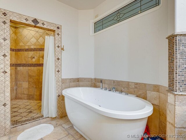 21125 State Highway 99 S, Stonewall, OK 74871 - bathroom with tile walls, a wainscoted wall, a freestanding bath, and a stall shower