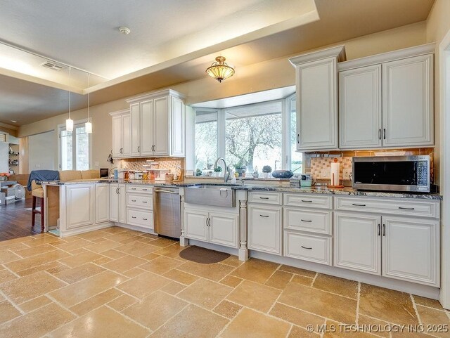 21125 State Highway 99 S, Stonewall, OK 74871 - kitchen with stainless steel appliances, backsplash, visible vents, a peninsula, and white cabinetry