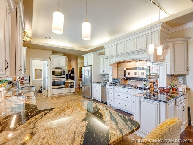 21125 State Highway 99 S, Stonewall, OK 74871 - kitchen featuring stainless steel appliances, a sink, dark stone counters, visible vents, and decorative backsplash