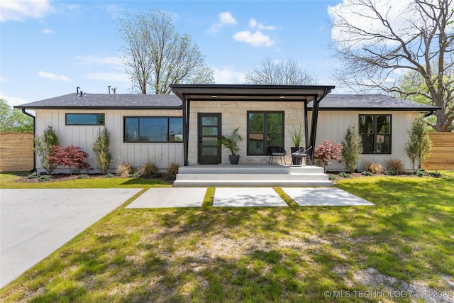 rear view of property featuring a wooden deck, a lawn, board and batten siding, and fence