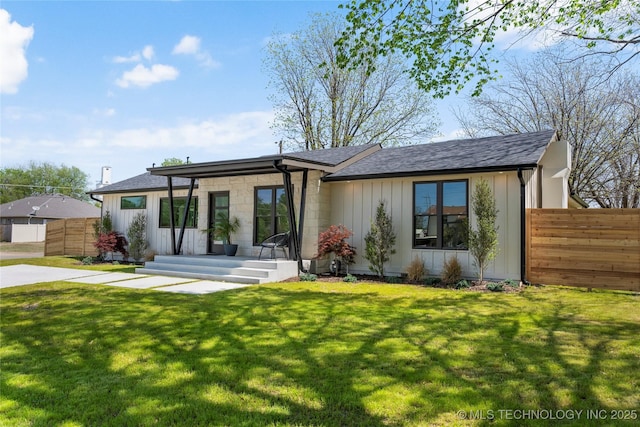 rear view of house with a lawn, fence, and board and batten siding