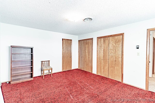 2445 E 156th St N, Skiatook, OK 74070 - unfurnished bedroom featuring carpet floors, a textured ceiling, and two closets