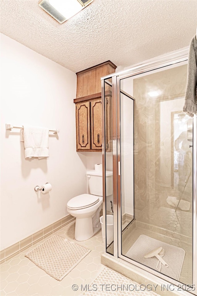 2445 E 156th St N, Skiatook, OK 74070 - bathroom featuring a shower stall, a textured ceiling, toilet, and tile patterned floors