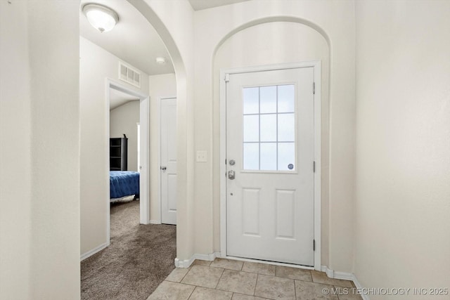 7201 S Joshua Ave, Broken Arrow, OK 74011 - doorway to outside with visible vents, light tile patterned floors, arched walkways, baseboards, and light colored carpet