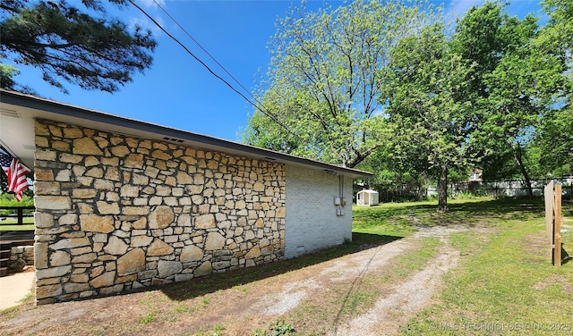 view of home's exterior with brick siding, a lawn, and fence