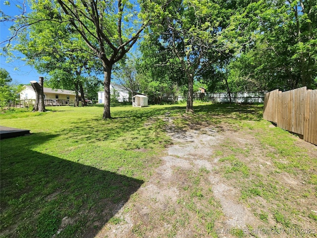 view of yard with fence, a storage unit, and an outdoor structure