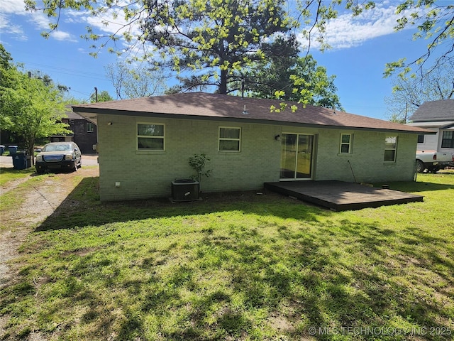 back of property featuring a lawn, central AC unit, brick siding, and a deck