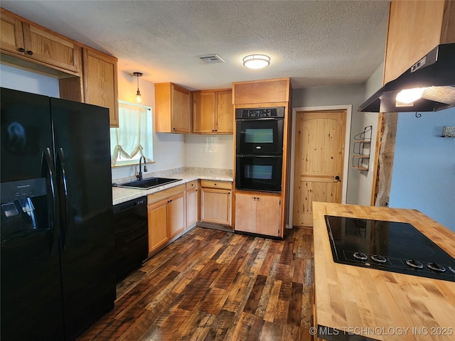 kitchen featuring a sink, dark wood-style flooring, visible vents, under cabinet range hood, and black appliances