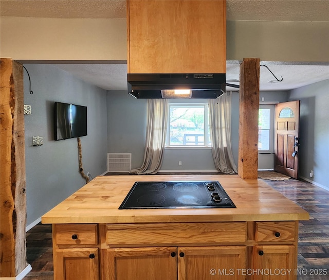kitchen featuring under cabinet range hood, butcher block countertops, a textured ceiling, and black electric cooktop