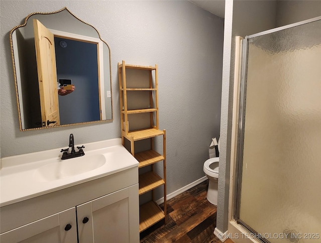 bathroom featuring vanity, wood finished floors, a shower stall, and toilet