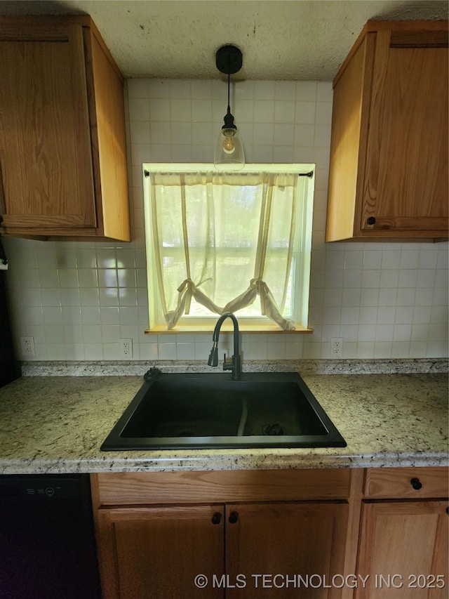 kitchen with brown cabinets, backsplash, light countertops, dishwasher, and a sink