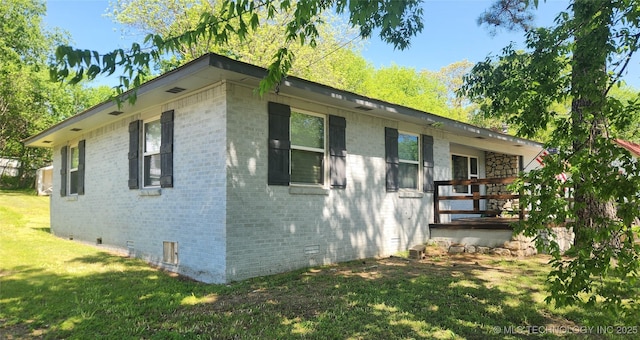 view of side of property featuring brick siding, a yard, and crawl space