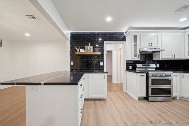 1136 S Evanston Ave, Tulsa, OK 74104 - kitchen featuring range with two ovens, under cabinet range hood, a peninsula, decorative backsplash, and white cabinets