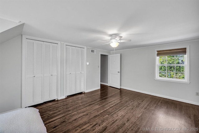 3334 S Wheeling Ave, Tulsa, OK 74105 - unfurnished bedroom featuring visible vents, ceiling fan, baseboards, dark wood finished floors, and two closets
