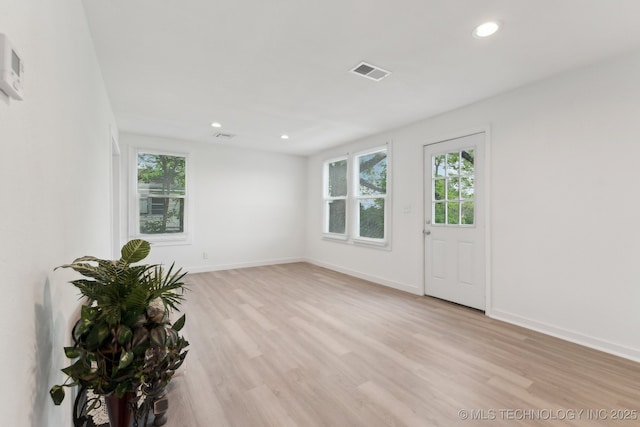 empty room with visible vents, a wealth of natural light, and light wood-type flooring