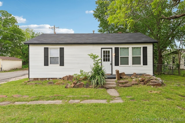 view of front of property with a front lawn, a shingled roof, and fence