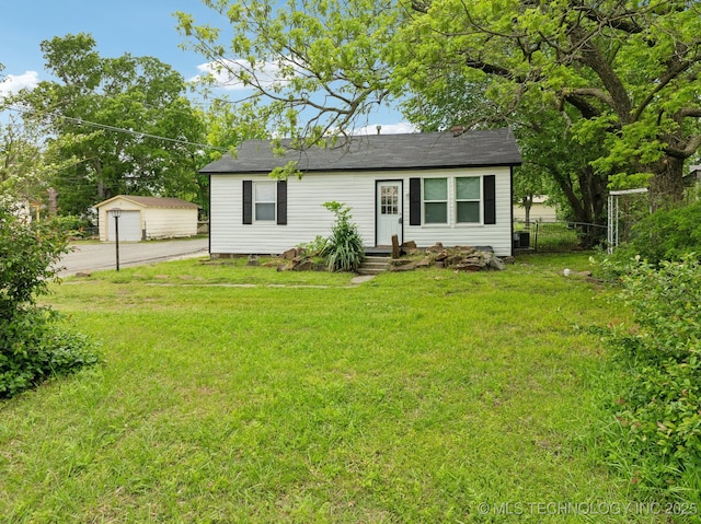 view of front facade featuring driveway, an outbuilding, fence, a front lawn, and a garage