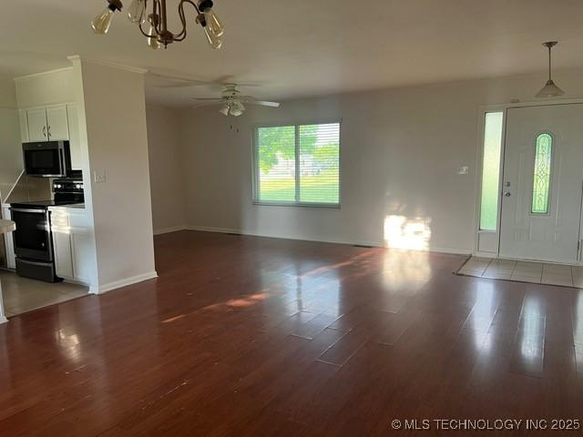 unfurnished living room featuring light wood-style floors, baseboards, and ceiling fan with notable chandelier