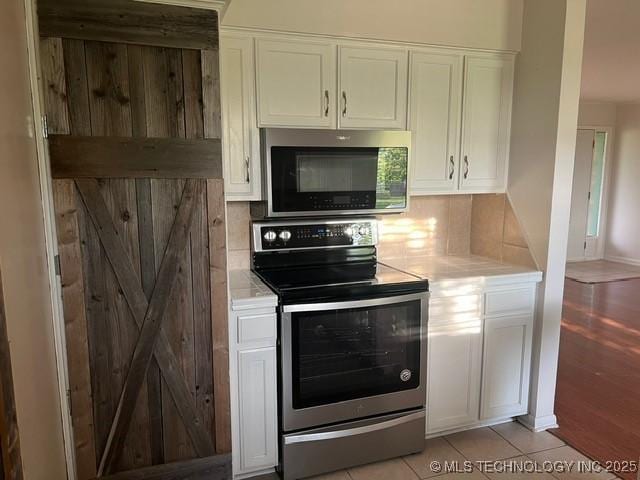 kitchen with light countertops, white cabinetry, appliances with stainless steel finishes, and backsplash