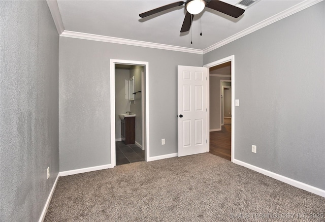 unfurnished bedroom featuring carpet floors, ornamental molding, baseboards, ceiling fan, and ensuite bath