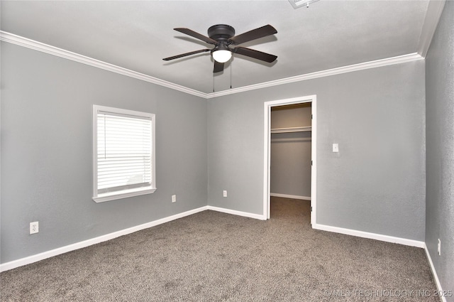 unfurnished bedroom with crown molding, baseboards, a walk in closet, and carpet floors