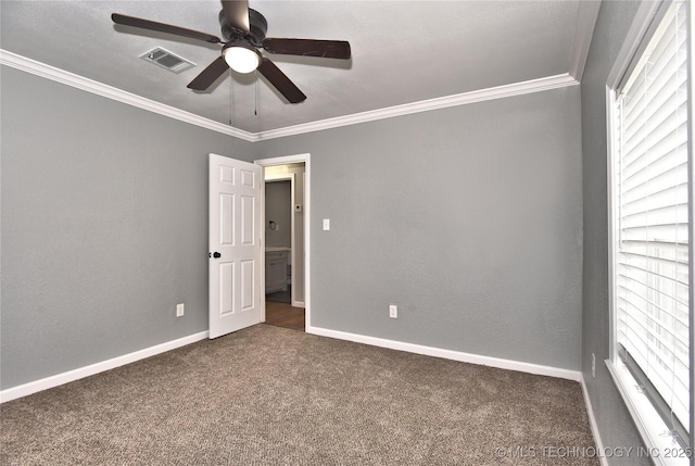 empty room with visible vents, ornamental molding, a ceiling fan, and dark colored carpet