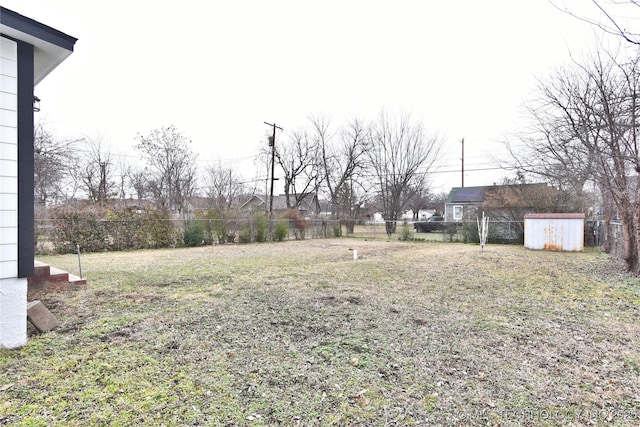 view of yard featuring a storage unit, an outdoor structure, and fence