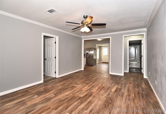 empty room featuring dark wood-style flooring, a ceiling fan, baseboards, visible vents, and ornamental molding