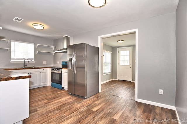 kitchen with open shelves, a sink, wood counters, stainless steel appliances, and wall chimney exhaust hood