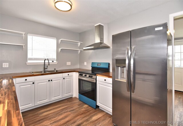 kitchen featuring wall chimney range hood, open shelves, a sink, butcher block counters, and stainless steel appliances