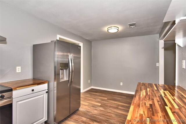 kitchen with butcher block counters, baseboards, white cabinets, dark wood finished floors, and stainless steel appliances
