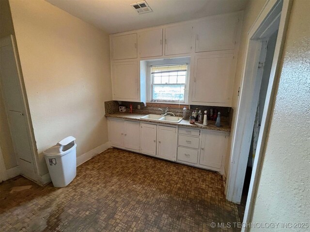 kitchen with visible vents, a sink, and white cabinetry