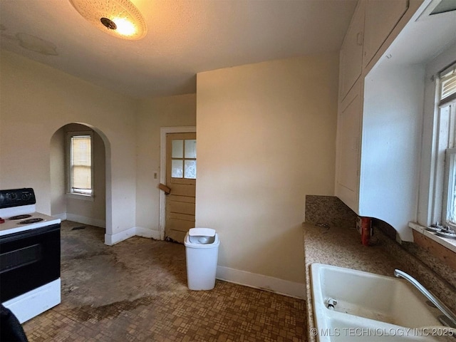 interior space with a bath, baseboards, and a sink