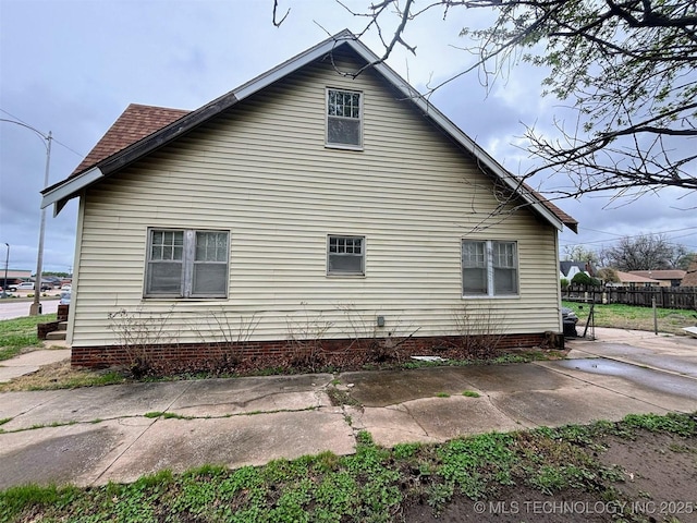 view of property exterior with fence and roof with shingles