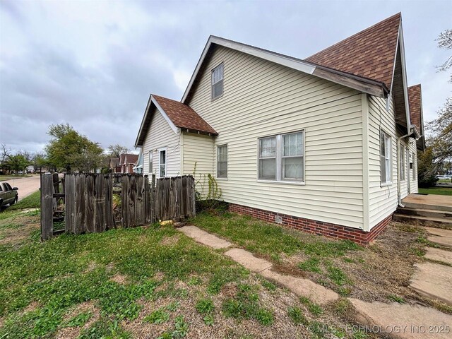 view of property exterior featuring a shingled roof and fence