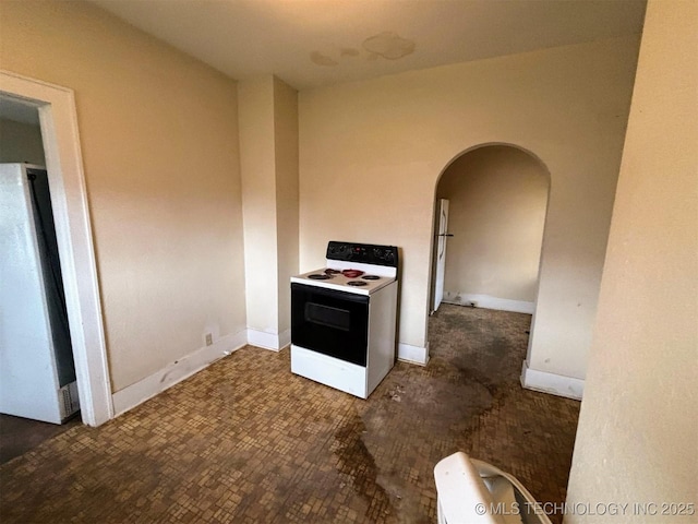 kitchen featuring white electric stove, baseboards, freestanding refrigerator, and arched walkways