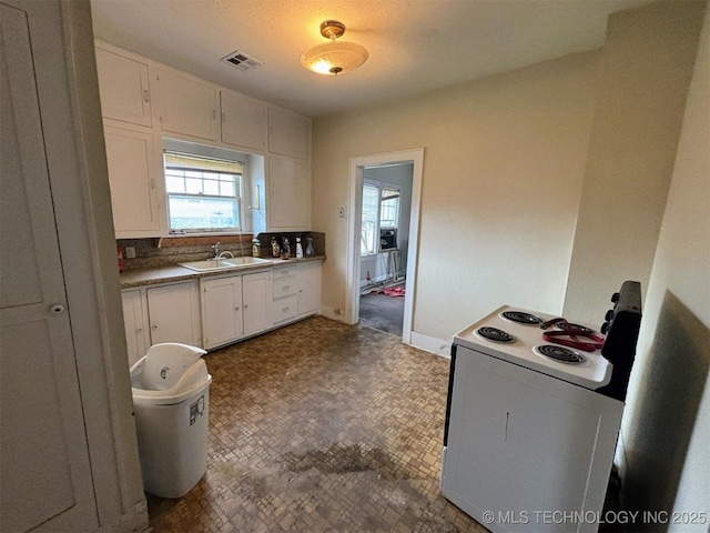kitchen with white cabinets, a sink, baseboards, visible vents, and white range with electric stovetop